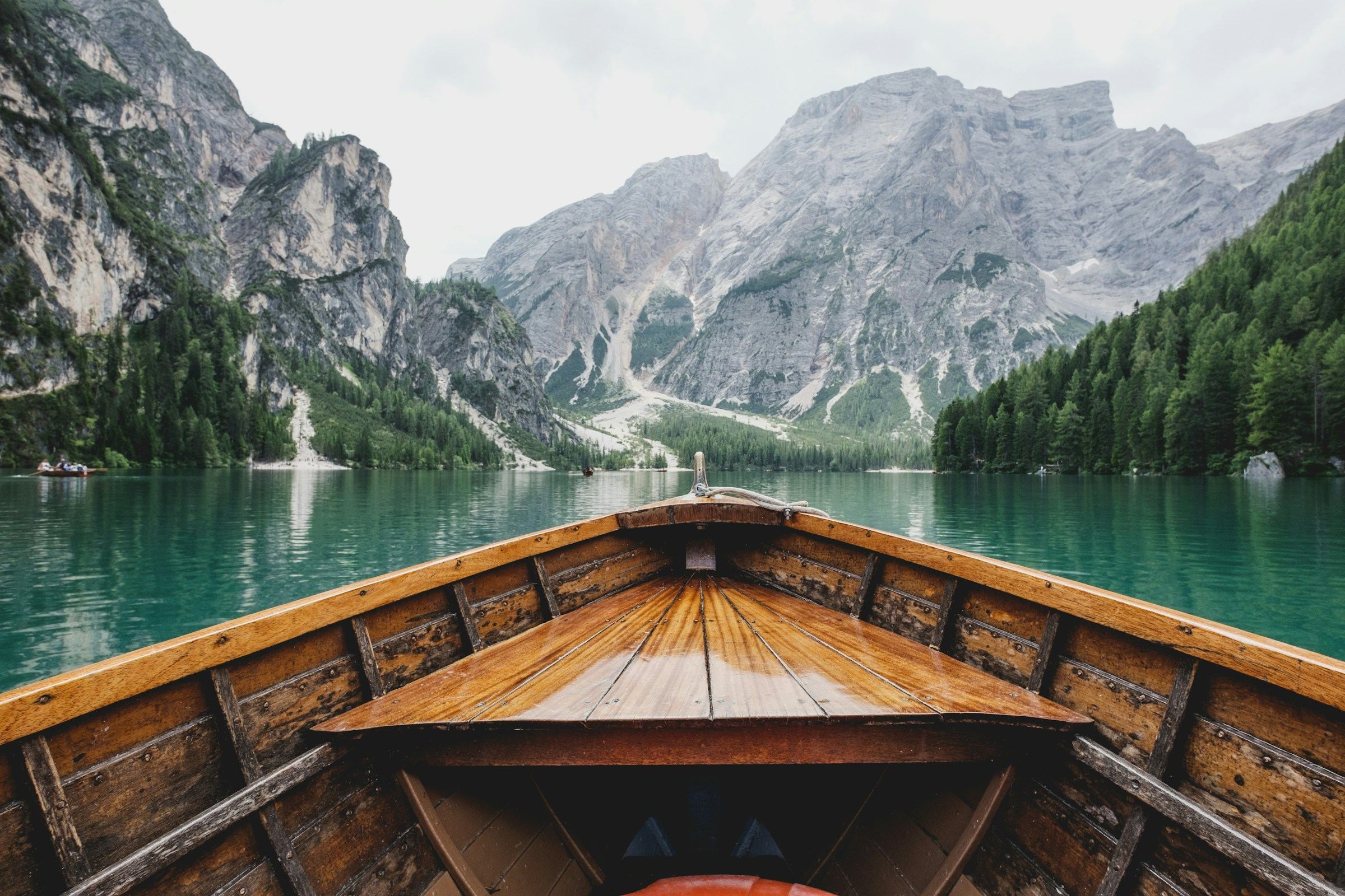 Looking forward from a wooden boat across a still alpine lake